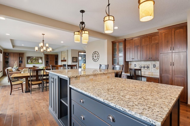 2919 Hilltop Dr, Chaska, MN 55318 - kitchen with a center island, open floor plan, light wood-type flooring, hanging light fixtures, and light stone counters