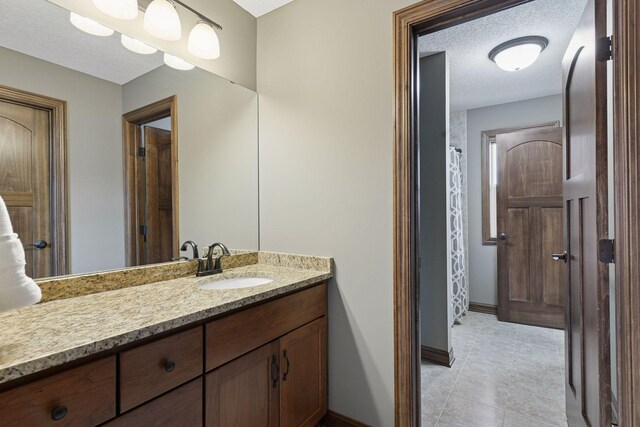 2919 Hilltop Dr, Chaska, MN 55318 - bathroom featuring baseboards, vanity, a textured ceiling, tile patterned flooring, and curtained shower