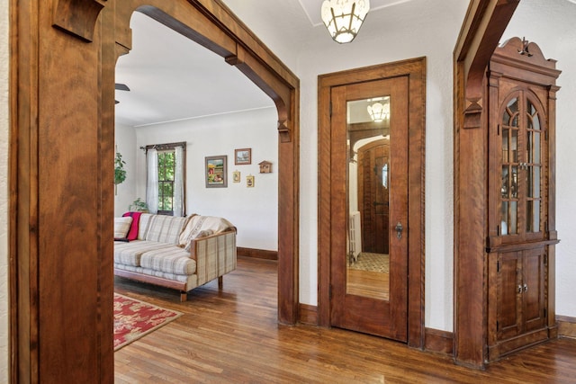 entrance foyer featuring arched walkways, wood finished floors, and baseboards