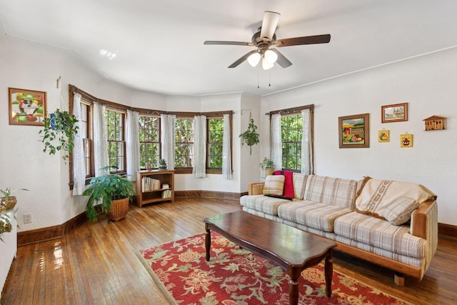 living area featuring baseboards, ceiling fan, and wood-type flooring