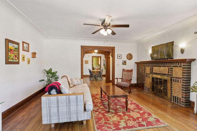 living area featuring ceiling fan, wood finished floors, a fireplace, and baseboards