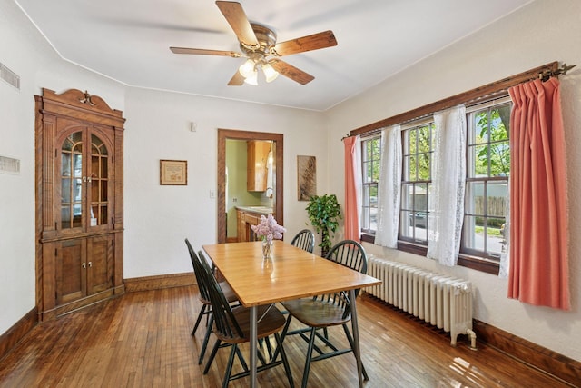 dining room featuring radiator heating unit, a ceiling fan, hardwood / wood-style floors, and baseboards