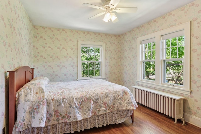 bedroom with radiator heating unit, wood finished floors, and a ceiling fan