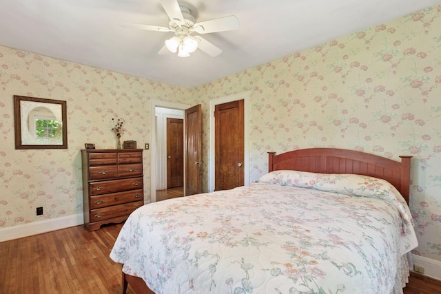 bedroom with wood finished floors, baseboards, a ceiling fan, and wallpapered walls