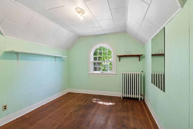 additional living space featuring radiator heating unit, hardwood / wood-style floors, lofted ceiling, and baseboards