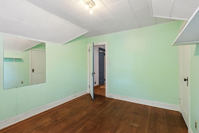 unfurnished room with dark wood-type flooring and baseboards