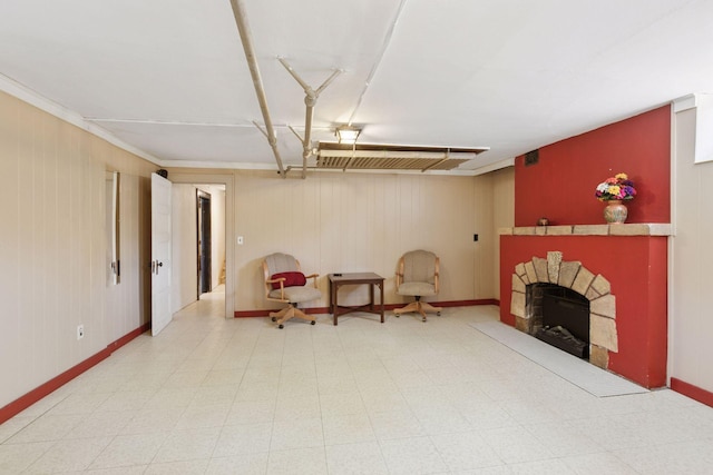 sitting room featuring a fireplace, baseboards, wooden walls, and tile patterned floors