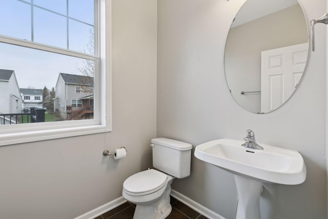 half bath featuring toilet, baseboards, a sink, and tile patterned flooring