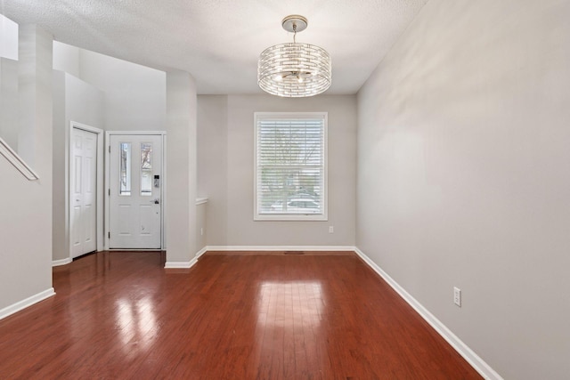 interior space featuring baseboards, an inviting chandelier, and wood finished floors