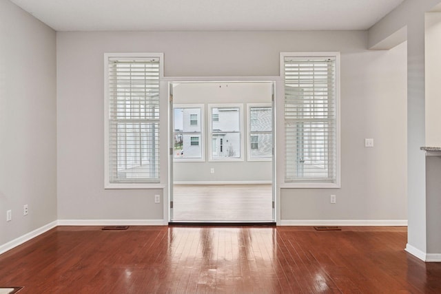 spare room featuring baseboards, visible vents, and hardwood / wood-style floors