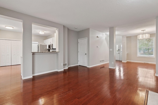 unfurnished living room with baseboards, dark wood finished floors, and visible vents
