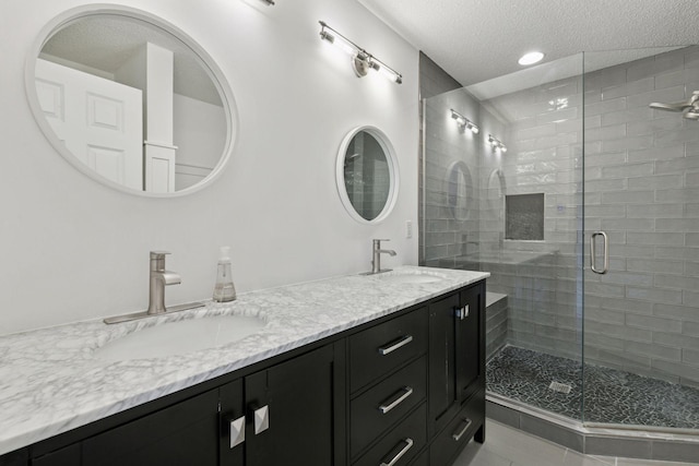 bathroom featuring a sink, double vanity, a stall shower, and a textured ceiling