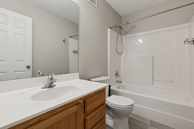 bathroom featuring a textured ceiling, visible vents, vanity, toilet, and  shower combination