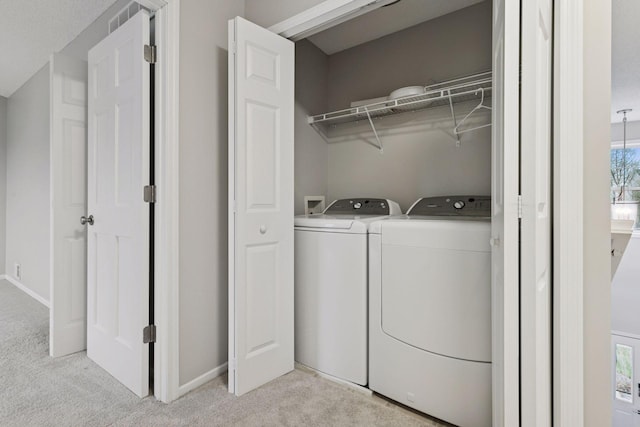 laundry room featuring a wealth of natural light, laundry area, washing machine and dryer, and light carpet