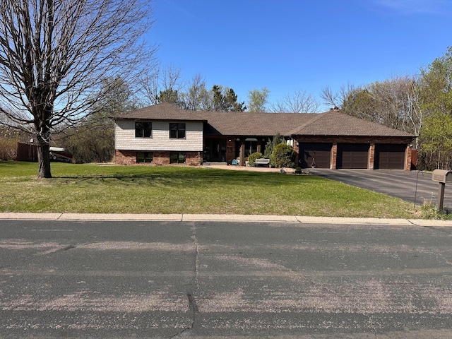 tri-level home featuring brick siding, an attached garage, driveway, and a front lawn