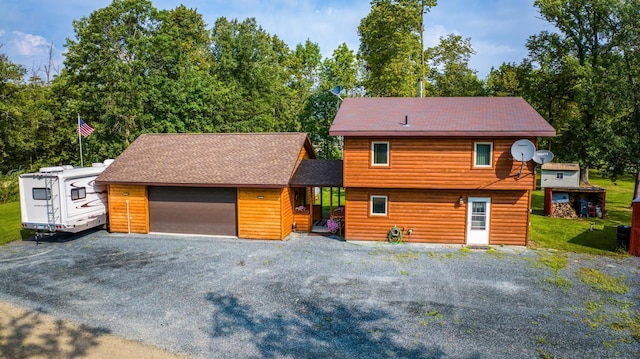 19675 Woody Ln NE, Kelliher, MN 56650 - view of front of house with roof with shingles, a detached garage, and faux log siding