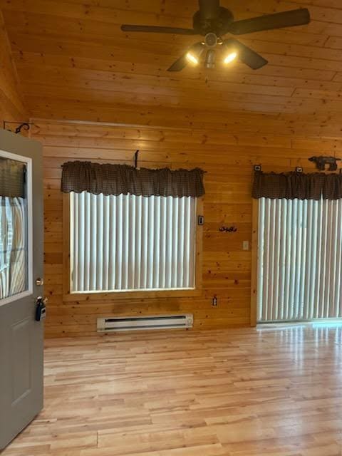 19675 Woody Ln NE, Kelliher, MN 56650 - unfurnished room featuring a wealth of natural light, wood walls, ceiling fan, and wood finished floors