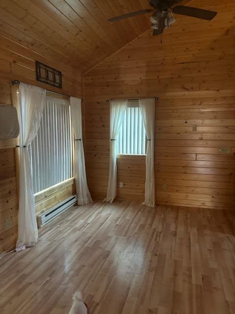 19675 Woody Ln NE, Kelliher, MN 56650 - interior space with wood walls, lofted ceiling, wood finished floors, a ceiling fan, and baseboard heating