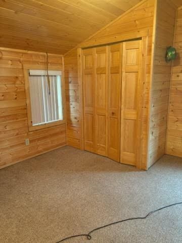 19675 Woody Ln NE, Kelliher, MN 56650 - unfurnished bedroom featuring vaulted ceiling, wood ceiling, wood walls, and light carpet