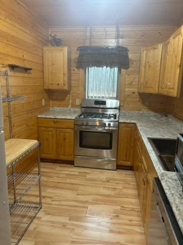 19675 Woody Ln NE, Kelliher, MN 56650 - kitchen featuring a sink, light wood-style flooring, wooden walls, and appliances with stainless steel finishes