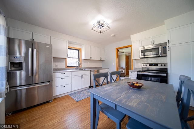 300 Carlson Rd, Cannon Falls, MN 55009 - kitchen with stainless steel appliances, decorative backsplash, light wood finished floors, and a sink