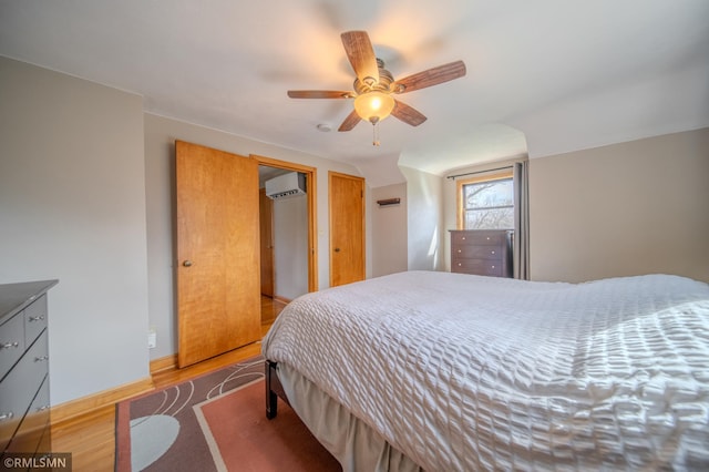 300 Carlson Rd, Cannon Falls, MN 55009 - bedroom with a wall mounted air conditioner, a ceiling fan, wood finished floors, and baseboards