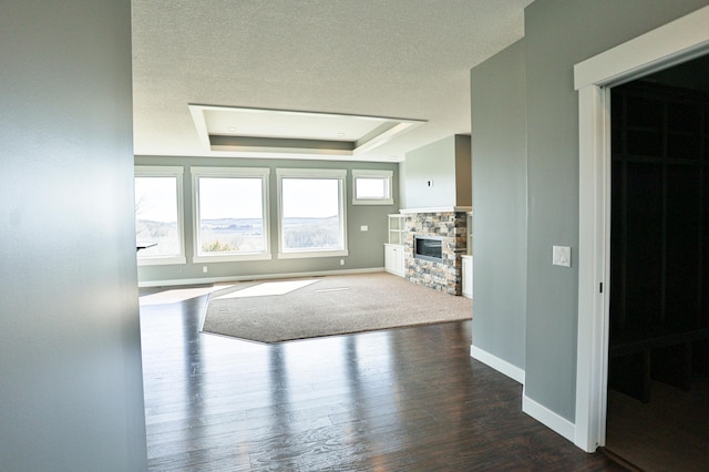 203 Walnut Hill Way, Troy Twp, WI 54022 - unfurnished living room featuring baseboards, a stone fireplace, dark wood-type flooring, a textured ceiling, and a tray ceiling