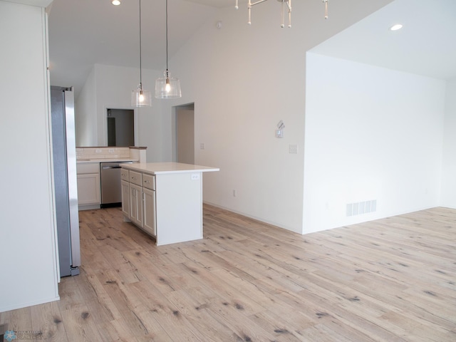 kitchen featuring light wood-style floors, light countertops, high vaulted ceiling, appliances with stainless steel finishes, and hanging light fixtures