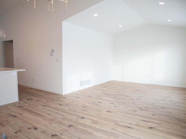spare room featuring light wood-type flooring, vaulted ceiling, visible vents, and recessed lighting