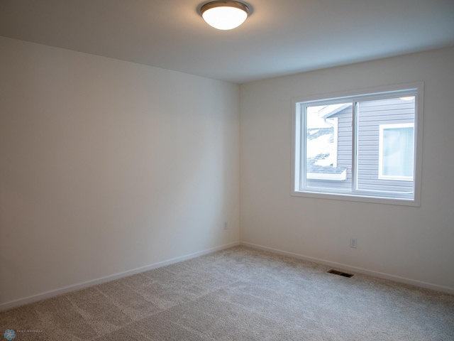 unfurnished room with baseboards, visible vents, and light colored carpet
