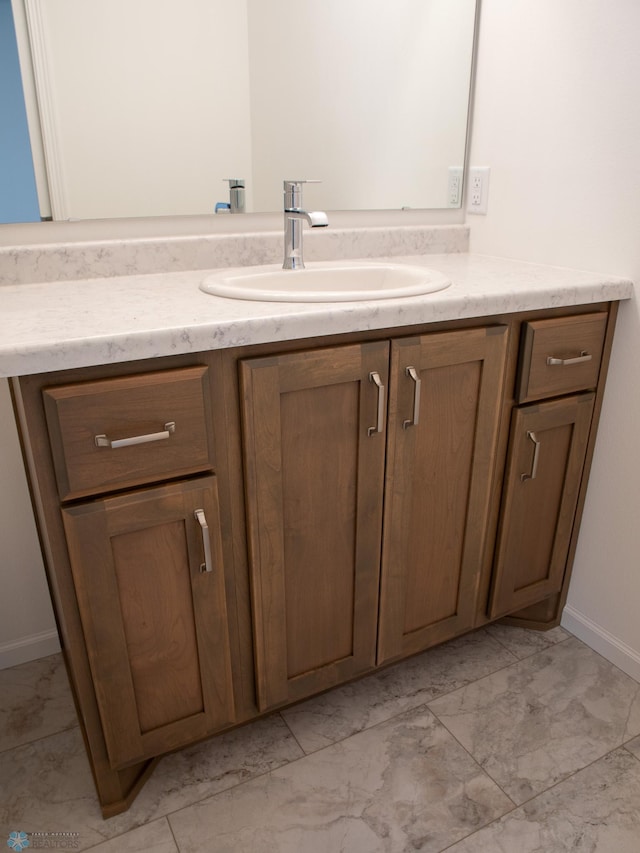 bathroom with baseboards, marble finish floor, and vanity