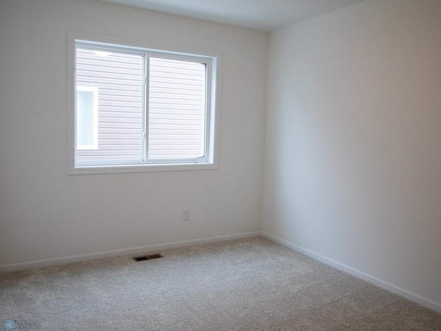 unfurnished room featuring carpet floors, visible vents, and baseboards