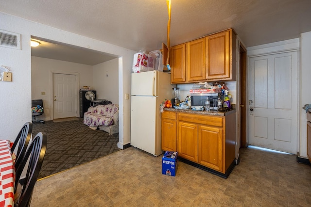606 11th St SE, Rochester, MN 55904 - kitchen with light floors, stainless steel microwave, freestanding refrigerator, brown cabinetry, and visible vents