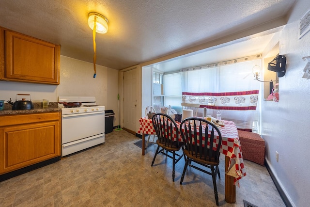 606 11th St SE, Rochester, MN 55904 - kitchen featuring tile patterned floors, brown cabinetry, white gas range, dark countertops, and a textured ceiling