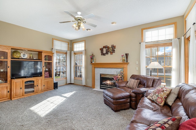 carpeted living room with a tile fireplace, a wealth of natural light, and ceiling fan