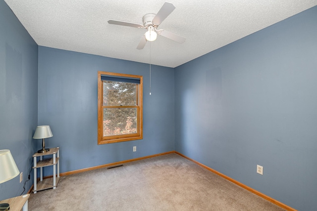 unfurnished room featuring carpet flooring, a textured ceiling, visible vents, baseboards, and ceiling fan