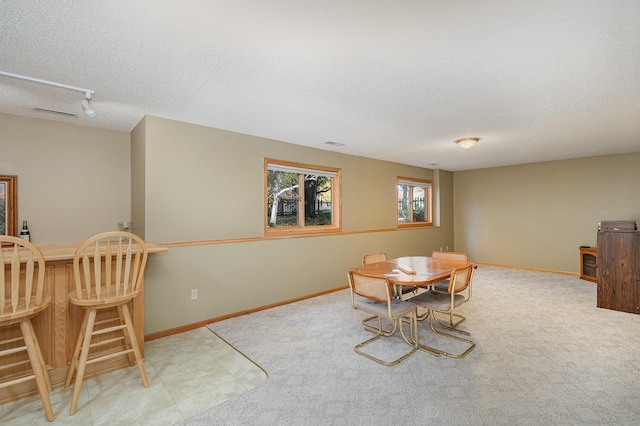 dining area featuring a dry bar, track lighting, baseboards, and a textured ceiling