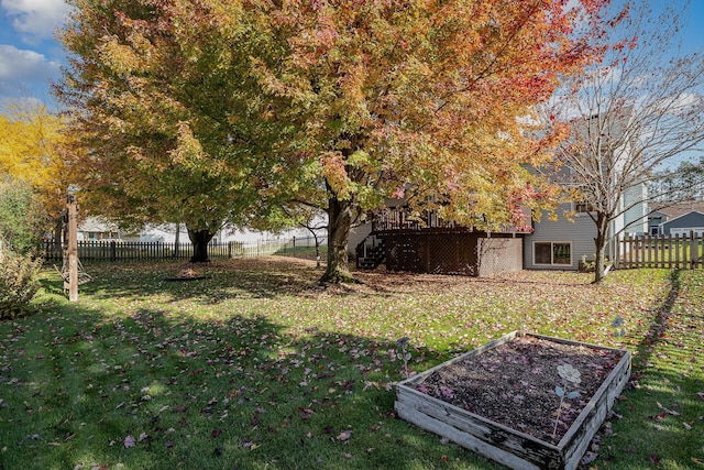 view of yard featuring a wooden deck, a garden, a fenced backyard, and stairway