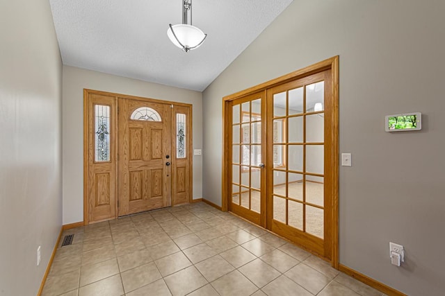 foyer entrance featuring light tile patterned floors, visible vents, baseboards, french doors, and lofted ceiling