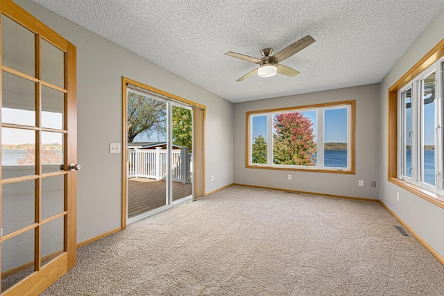 carpeted spare room with baseboards, visible vents, a ceiling fan, and a textured ceiling