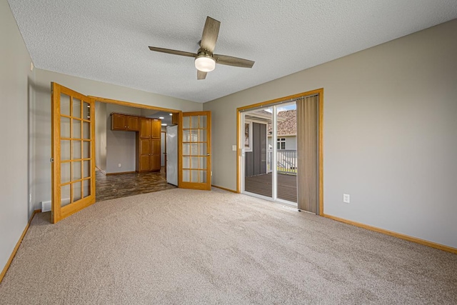 carpeted empty room featuring baseboards, a ceiling fan, a textured ceiling, and french doors