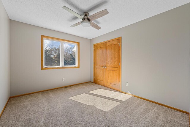 unfurnished bedroom with light colored carpet, a closet, a textured ceiling, and baseboards