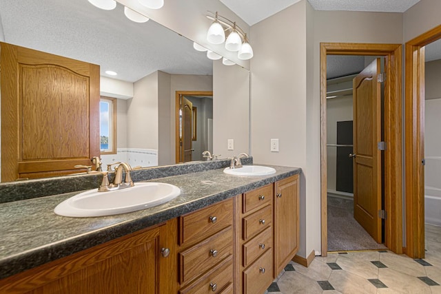 full bathroom featuring double vanity, a sink, and a textured ceiling