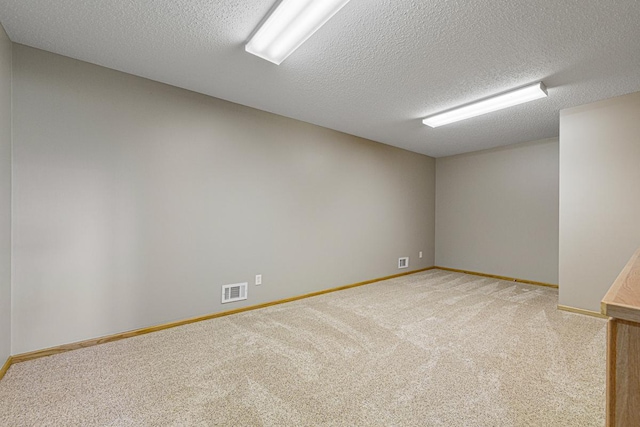 carpeted spare room featuring baseboards, visible vents, and a textured ceiling