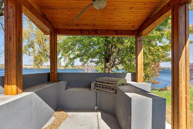 view of patio with area for grilling, a water view, and a ceiling fan