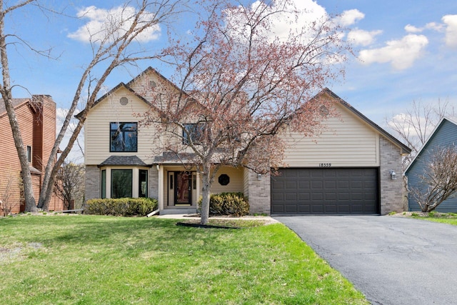 traditional home featuring driveway, a front lawn, brick siding, and an attached garage