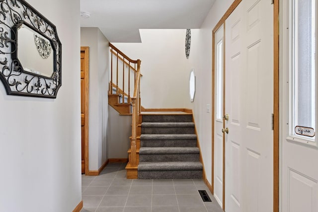 entrance foyer with light tile patterned floors, visible vents, stairway, and baseboards