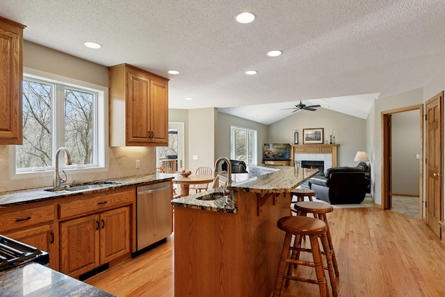 kitchen featuring light wood-style floors, a breakfast bar, stainless steel dishwasher, and a sink