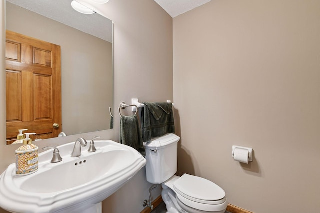 bathroom featuring toilet, a sink, and baseboards