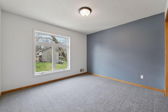 spare room with a textured ceiling, visible vents, carpet floors, and baseboards